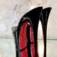 Black patent platform heels with clear straps. Red glitter on the arches and inside of heels. Black soles.