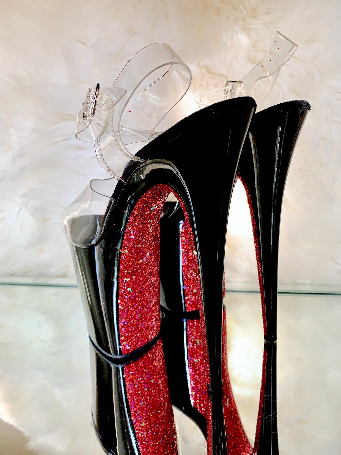 Black patent platform heels with clear straps. Red glitter on the arches and inside of heels. Black soles.