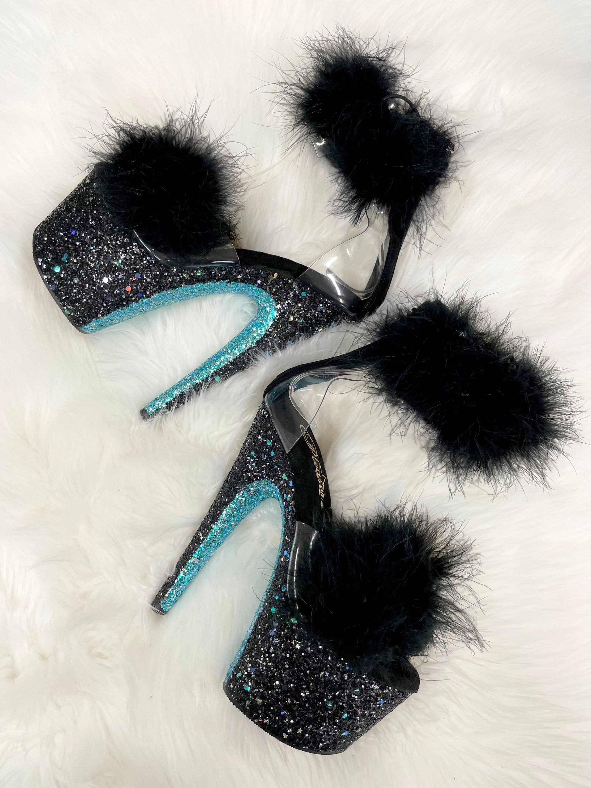 Black and baby blue glitter 7" Heels with baby blue glitter bottoms, and black glitter on the platform and heels, clear straps, black soles, black feathers over the toe straps, and black feathers around the ankle straps.