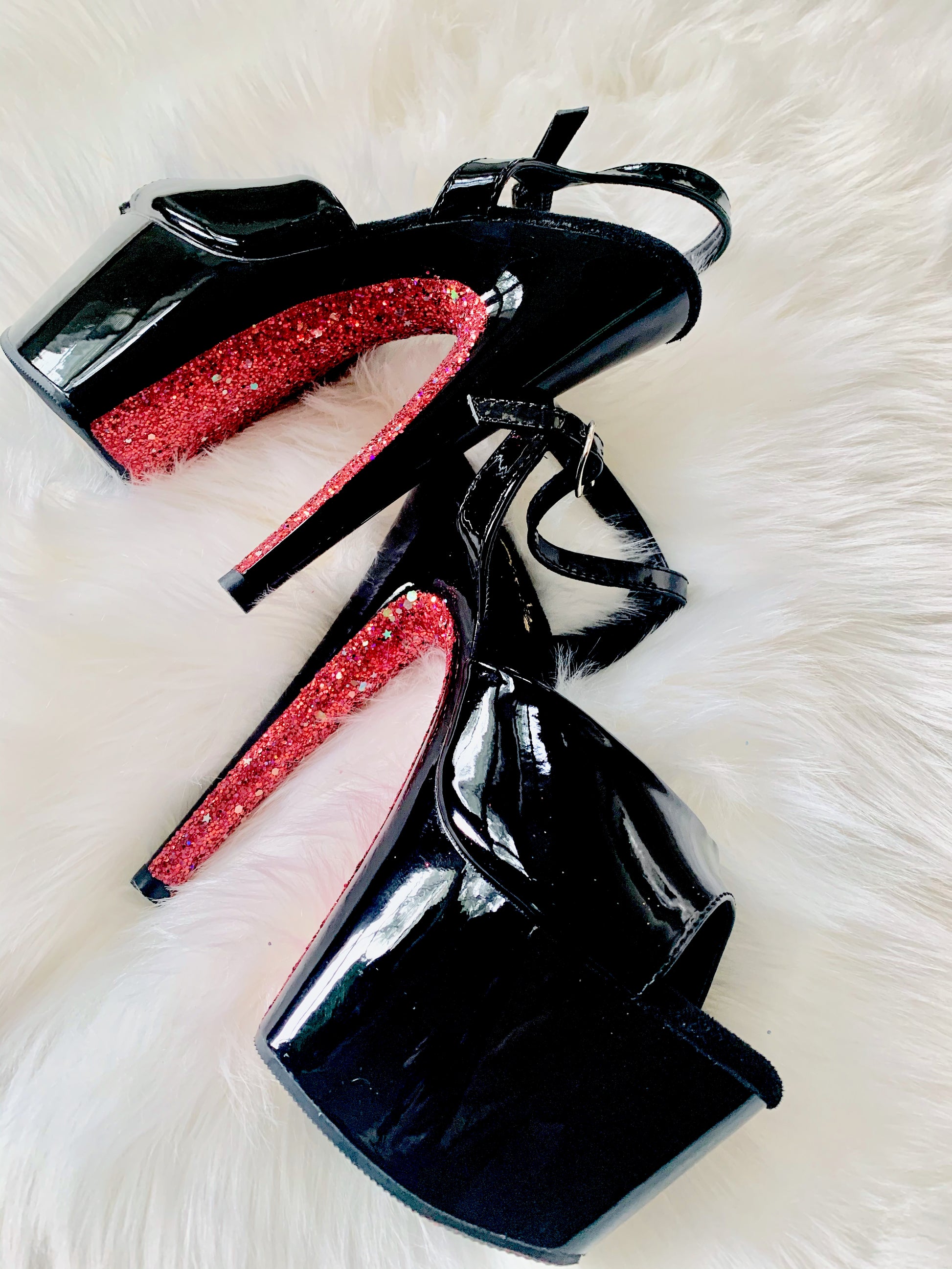 Black patent platform heels with black straps. Red glitter on the arches and inside of heels. Black soles.