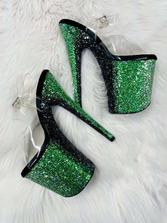 Platform heels with clear straps, and dual Ombre with green and black glitter. Shade of green starting at the front of the platform, and back of the heels, blending to black under the arch, and down the inside of the heels. Black soles.