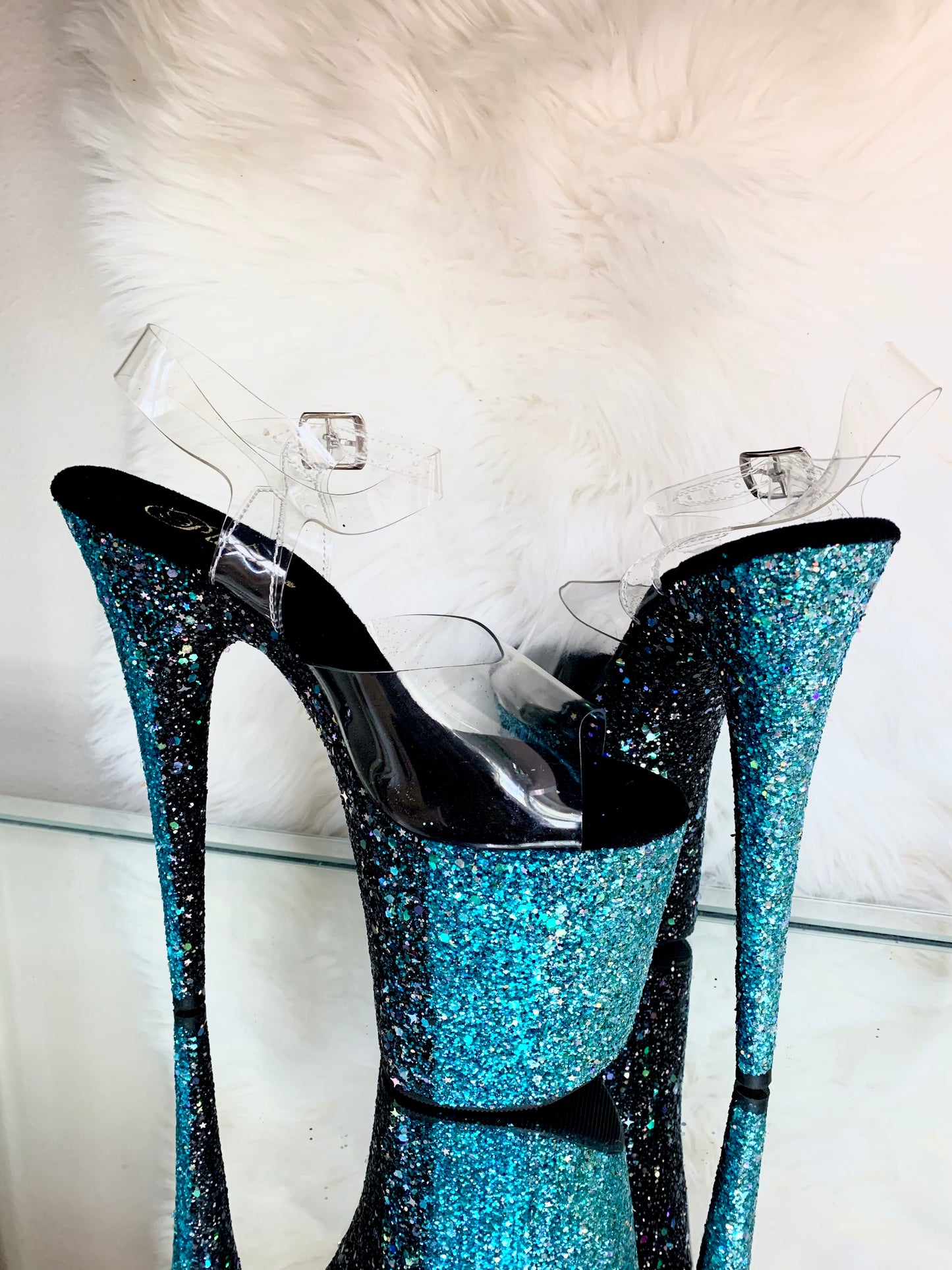 Platform heels with clear straps, and dual Ombre with turquoise and black glitter. Shades of turquoise starting at the front of the platform, and back of the heels, blending to black under the arch, and down the inside of the heels. Black soles.