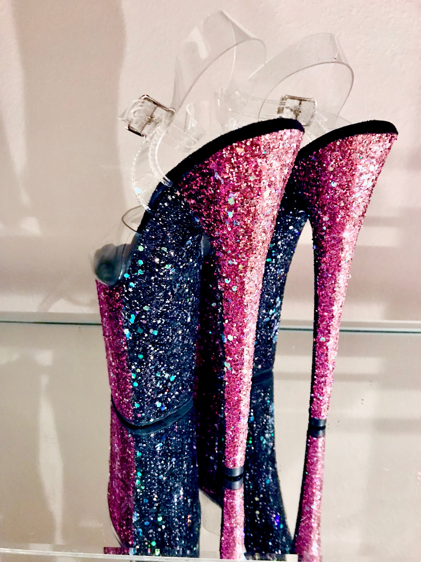 Platform heels with clear straps, and dual Ombre with blush, magenta, and black glitter. Shades of blush and magenta glitter starting at the front of the platform, and back of the heels, blending to black glitter under the arch, and down the inside of the heels. Black soles.